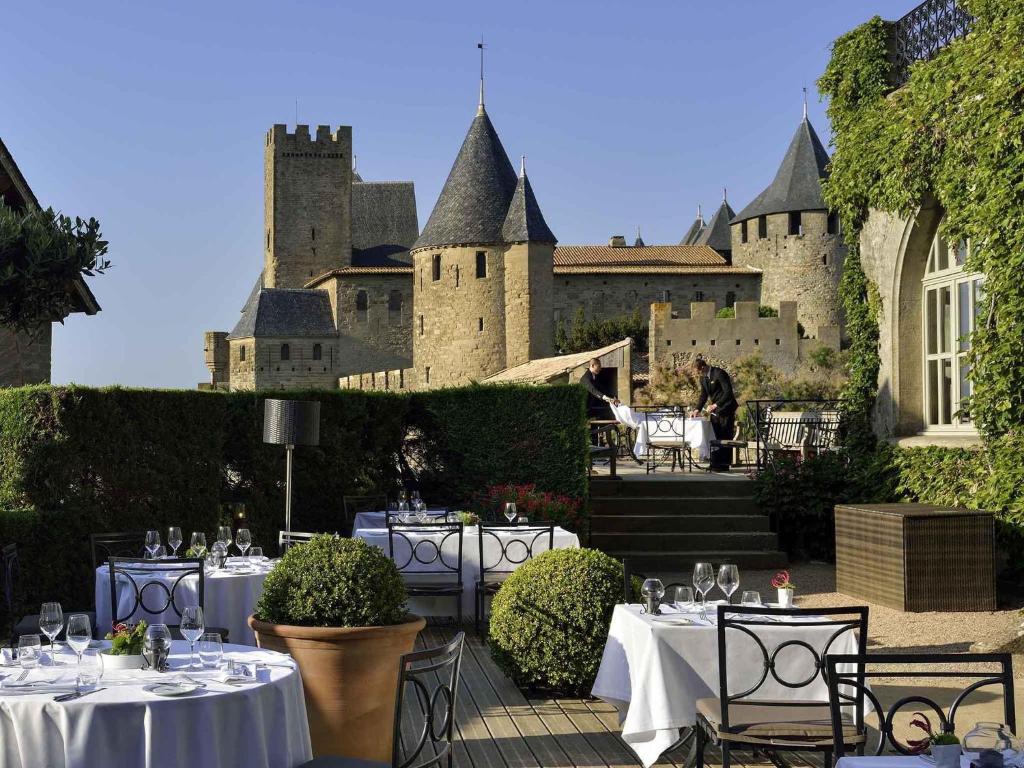 A hotel terrace of set tables looking toward a walled medieval town.