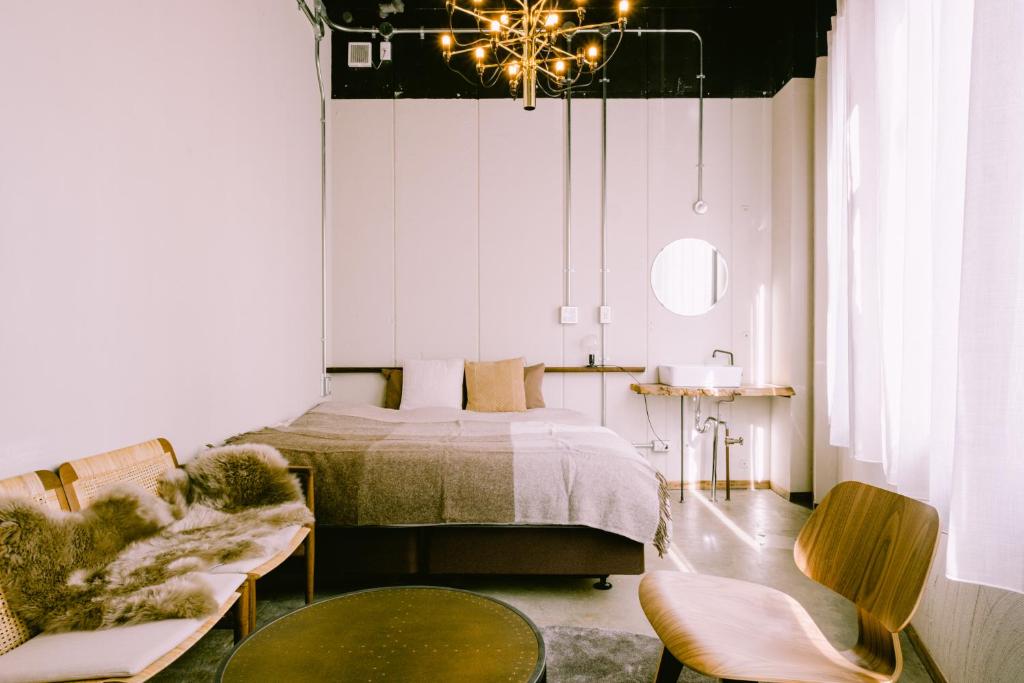 A light hotel room with a bed, wooden furniture and tall curtains.