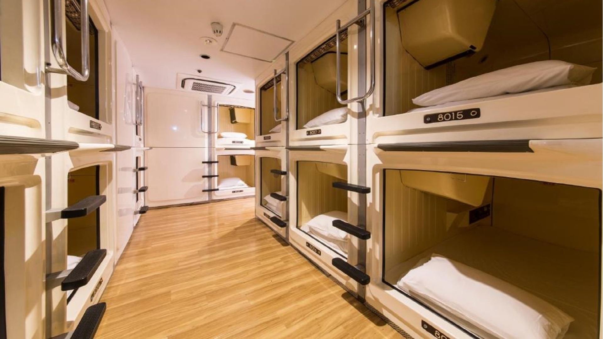 A corridor of stacked sleeping capsules with white bedding.