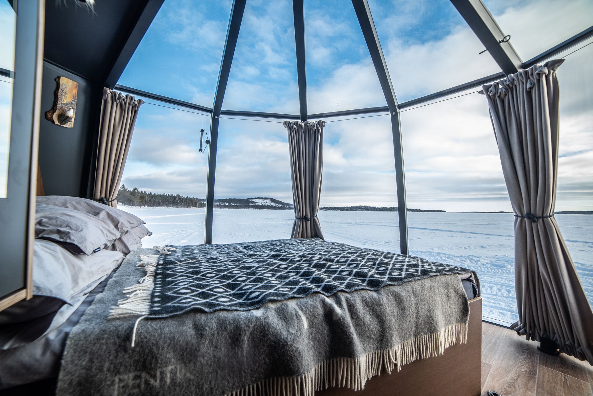 A glass-domed winter room looking out over a snow-covered lake.